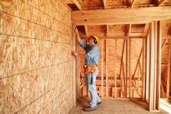 Construction worker building a new home wearing a yellow hard safty hat and a tool belt.